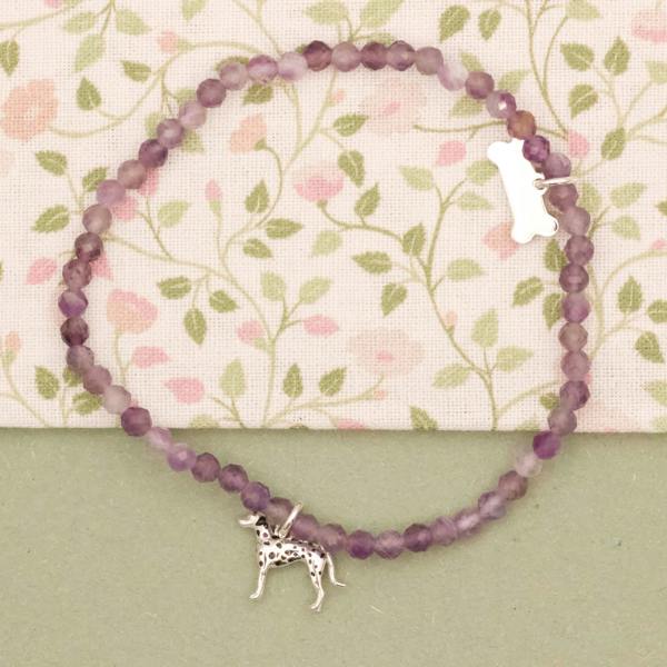 Purple beaded bracelet with a silver dalmatian dog charm on a floral background