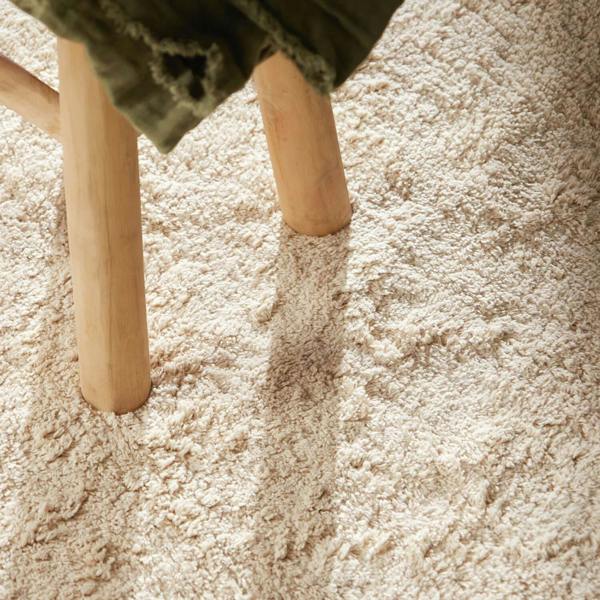 Close-up of a wooden stool on a textured beige carpet