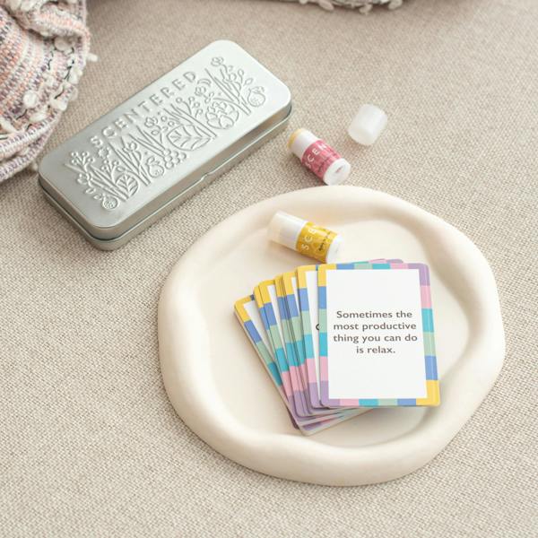 A tin box, a pack of cards, and two mini balms are resting on the sofa.