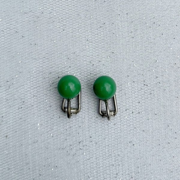 Green clip-on earrings, small round bead design, glossy green finish, silver-tone clip setting, minimalist vintage-inspired jewellery
