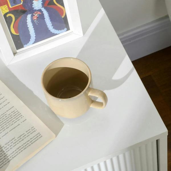 White two-drawer chest top corner with gold-tone ribbed side; mug on the surface