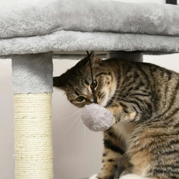 Grey cat tree perch with hanging ball and beige scratching post; tabby cat batting toy