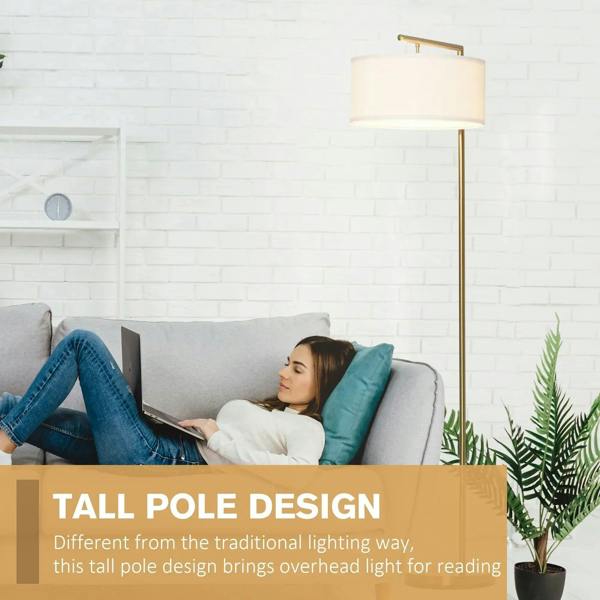 Tall gold floor lamp with white linen drum shade next to sofa