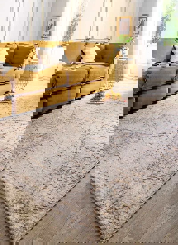 Abstract geometric rug in neutral tones of beige and grey, placed in a cozy living room with a yellow sofa.