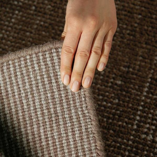 Hand touching a textured brown fabric with a blurred background