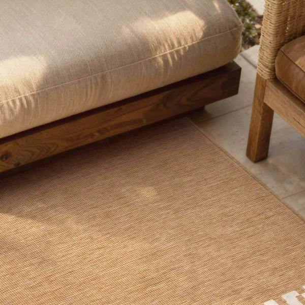 Beige outdoor rug with wooden furniture in the background