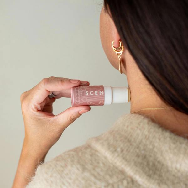 A woman holding a love balm to use on her neck