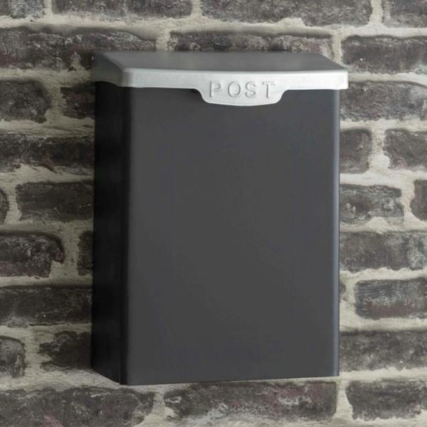 A wall-mounted carbon grey external post box with a silver galvanised steel lid featuring the word POST embossed on the front rim, fixed onto an old red-brick wall.