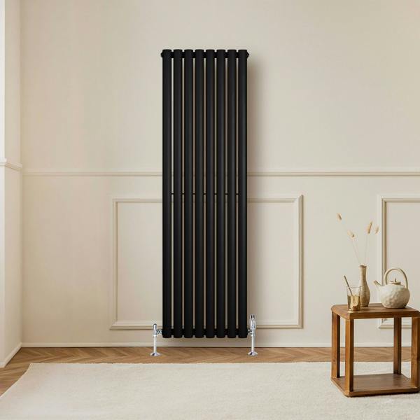 Sleek black oval single column radiator with chrome valves, standing tall against a neutral wall, enhancing modern interior decor
