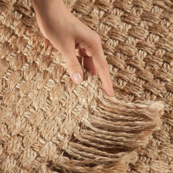 Hand touching a textured woven mat with fringes