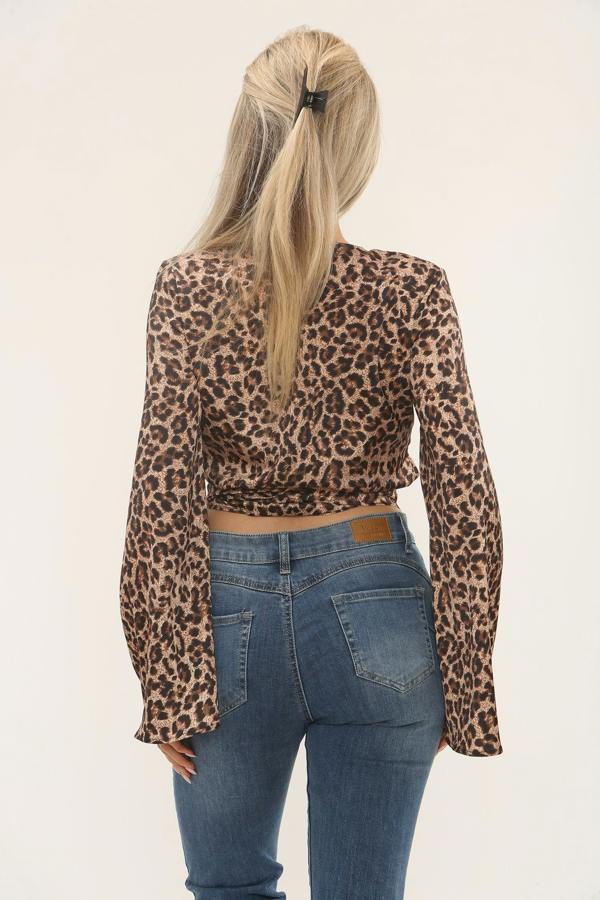 Person wearing a leopard print top and blue jeans on a beige background