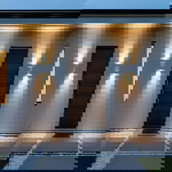 white up and down outside wall light mounted either side of the door on a modern home 