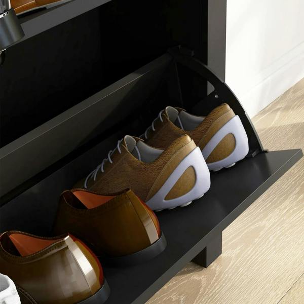 Interior view of black flip-door shoe cabinet with stored sneakers on the tray