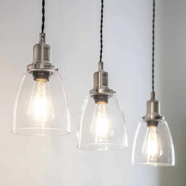 Three linear glass dome pendant lights with satin nickel fittings glowing against a neutral background by Abode Home & Gifts.