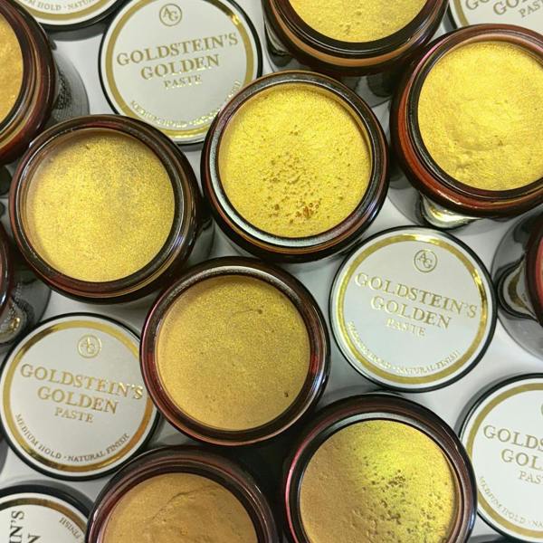 Opened jars of Goldstein's Golden Paste with visible gold pigment on a white background