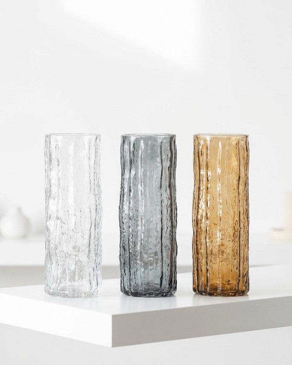 Three textured vases with flowers on a wooden surface