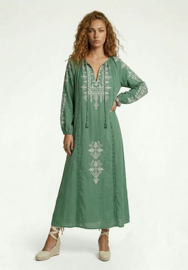 Woman wearing a green embroidered dress on a white background