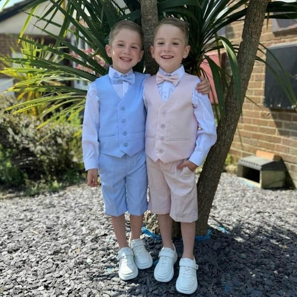 2 boys playing and smiling by a tree
