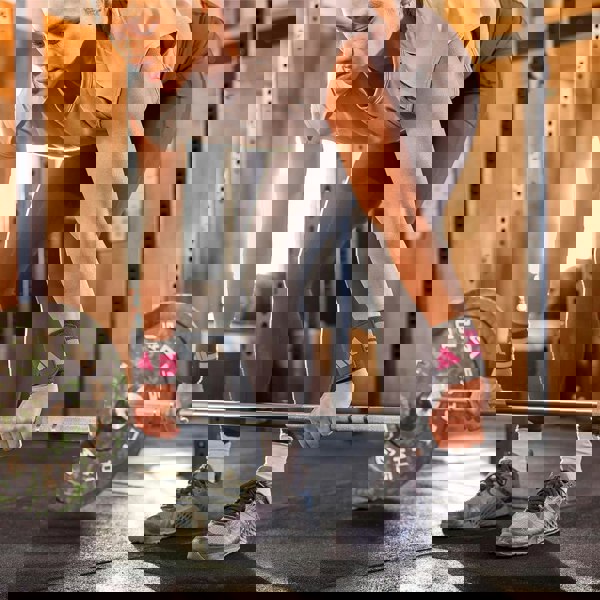 Person lifting a barbell in a gym setting wearing  adidas wrist wraps