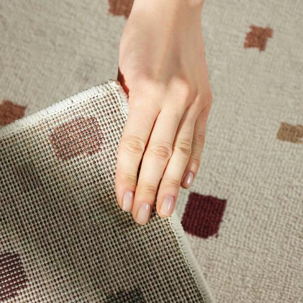 Hand holding a textured fabric with a pattern on a matching fabric background