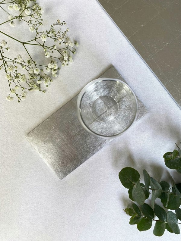 Silver double coaster on a white table surface