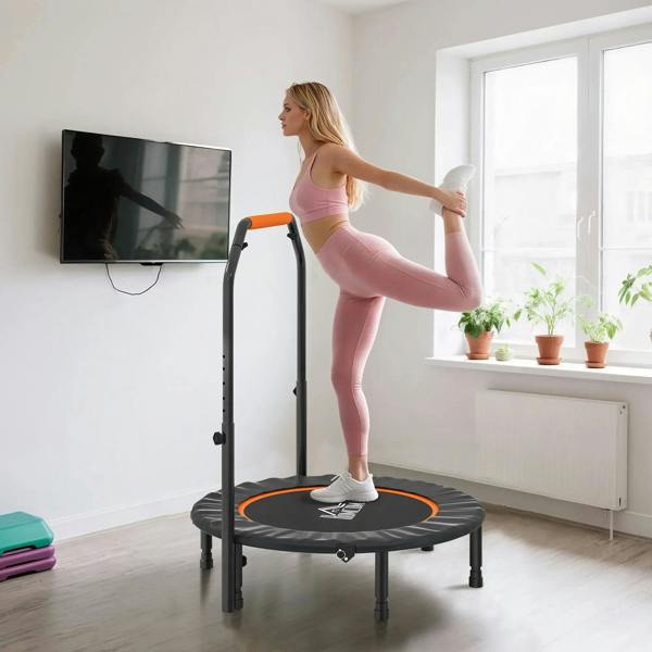 Orange-handled mini fitness trampoline with black rebound mat; person balancing on it
