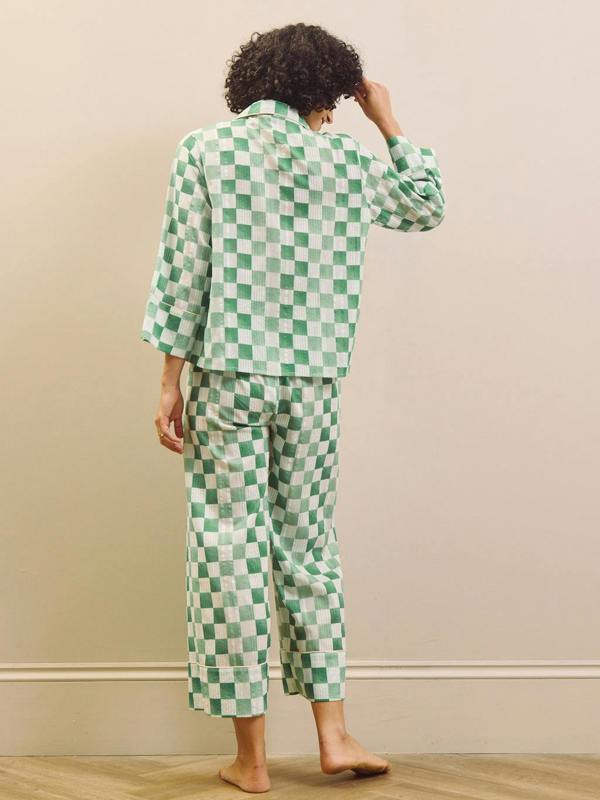 model wears green gingham check cropped pyjama set against a beige background