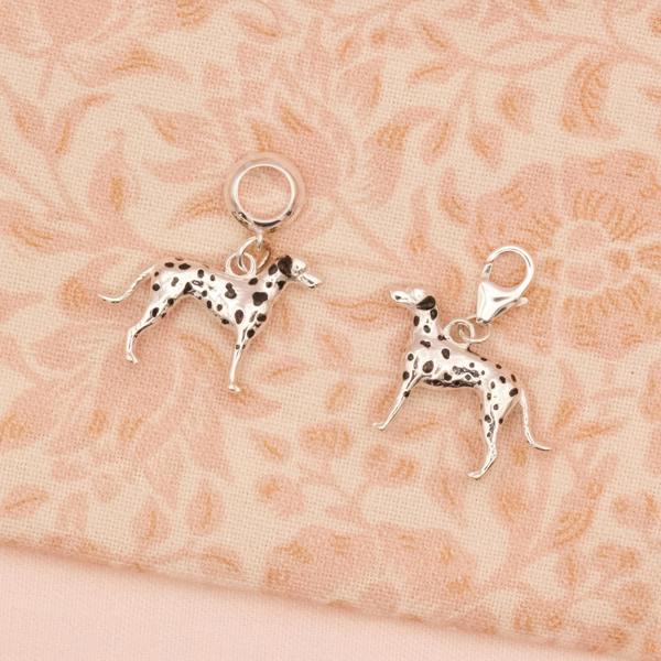 Two silver Dalmatian dog charms on a floral fabric background