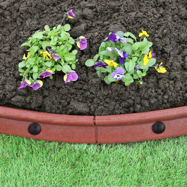 Flexible terracotta lawn edging with a smooth finish, outlining vibrant purple and yellow pansies against rich soil and green grass
