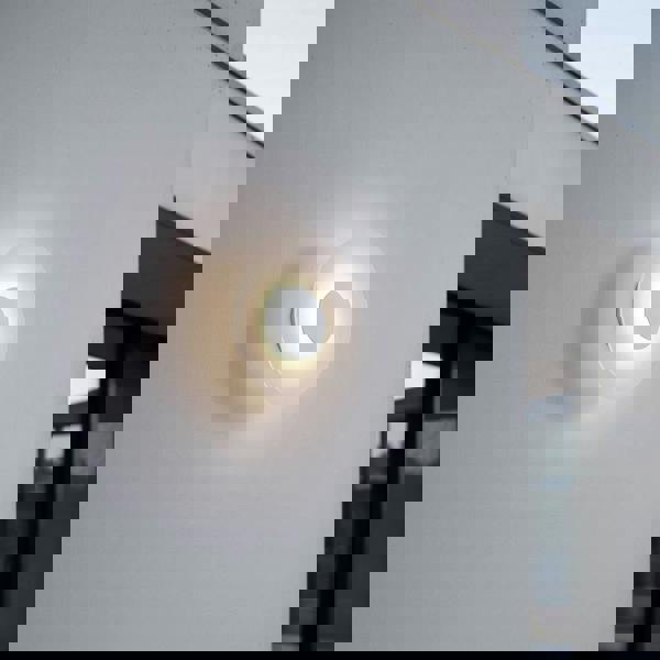 White round modern outdoor wall light mounted on a white wall of a modern home exterior