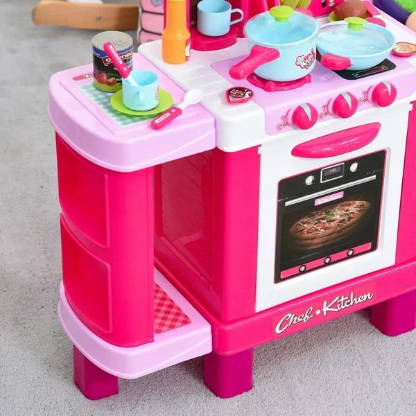 Close-up of pink and white toy oven, burners, and tabletop cookware with utensils.