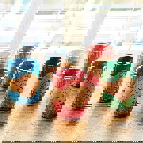 Five colorful Recycled Plastic Tumblers sitting on a wooden table.
