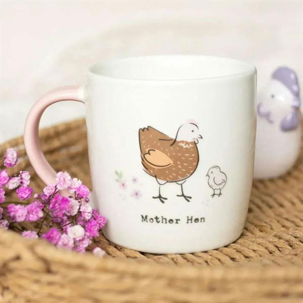 White ceramic mug with pink handle, brown mother hen and chick graphic, “Mother Hen”.