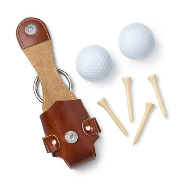 Flat lay view of an empty brown leather golf ball and tee holder pouch with snap buttons, shown alongside two white golf balls and four wooden golf tees on a white background.