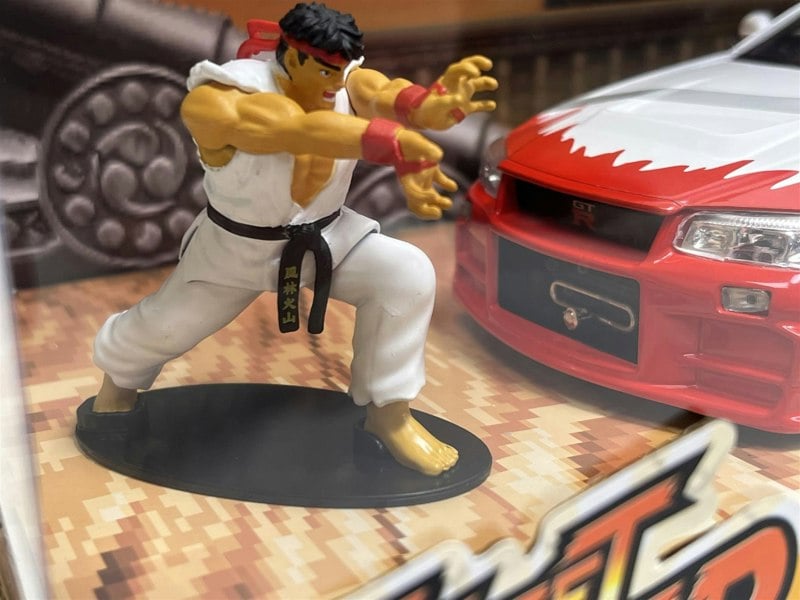 a toy figurine of a man in a white robe and a red car