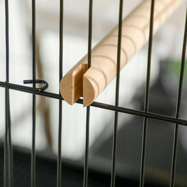 Wooden perch attached across black wire bars inside bird cage