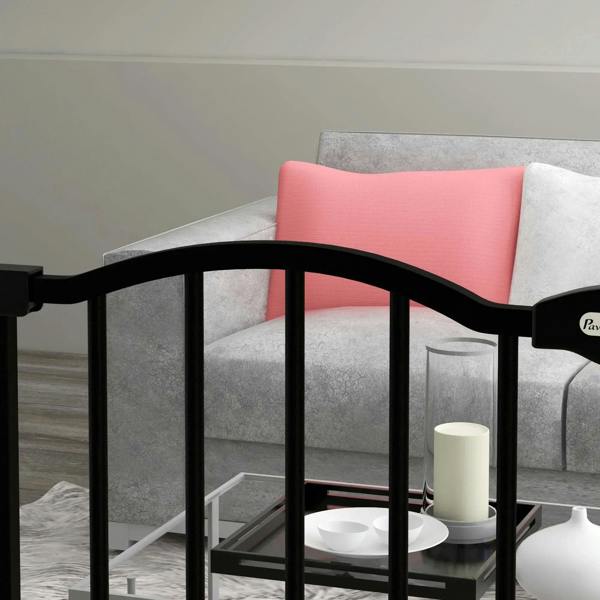 Black metal dog safety gate installed near a living room sofa, front corner view
