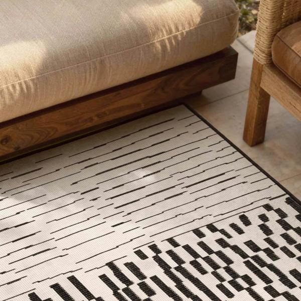 Patterned rug on a wooden floor with furniture in the background
