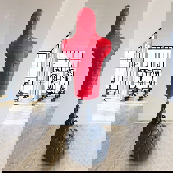 Red free-standing boxing dummy with a muscular torso design, mounted on a sturdy black base, ideal for training in a gym setting