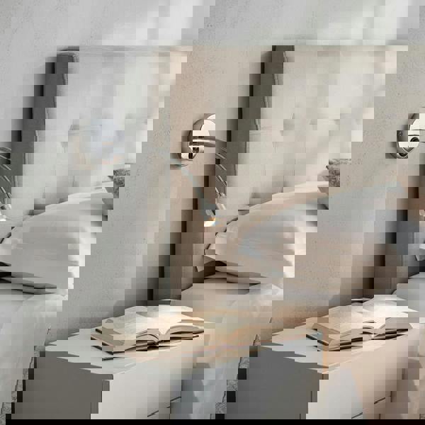 silver flexible reading lamp mounted on the wall next to a bed