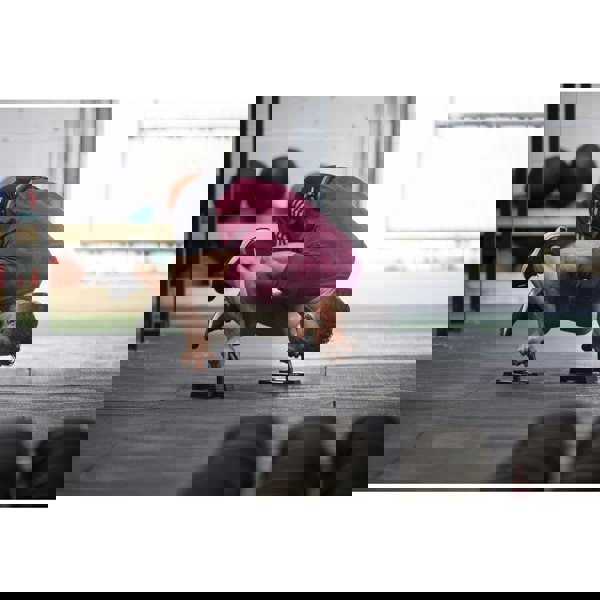 Person performing a push-up exercise with adidas push up bars on a gym floor.