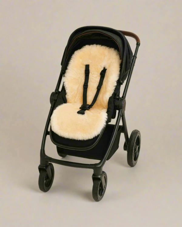 Black stroller with a beige sheepskin seat liner on a neutral background
