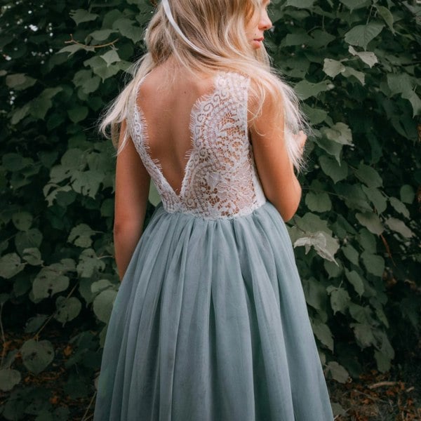 Girl wearing a sage green dress with a lace back against a leafy background