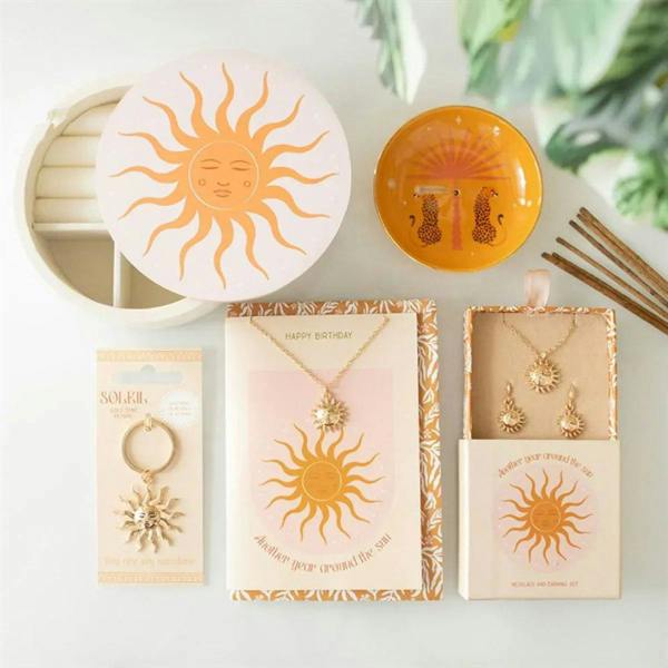 Sun-themed necklace and earring set in decorative box on flat lay display