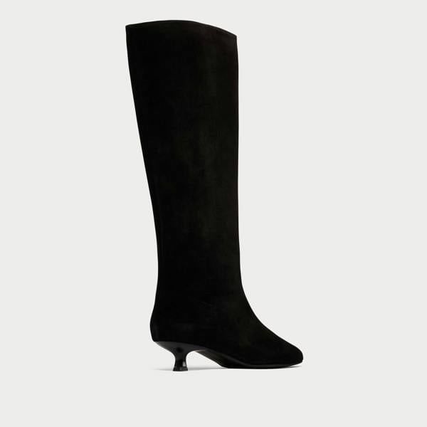 Black knee-high boot on a light gray background