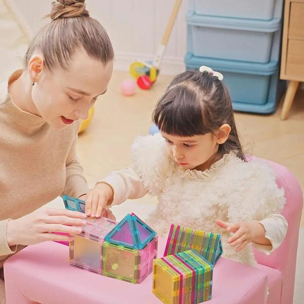 Pink toddler sofa chair with cushioned seat and armrests, kids playing with blocks