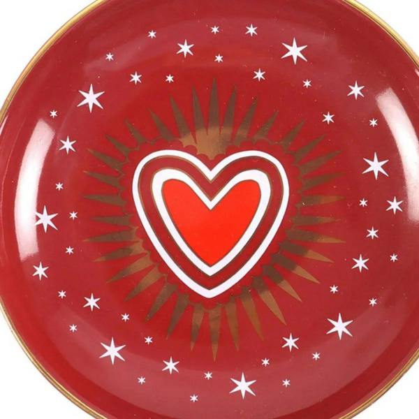 Close-up red trinket dish with gold rim, white sacred heart emblem and star pattern