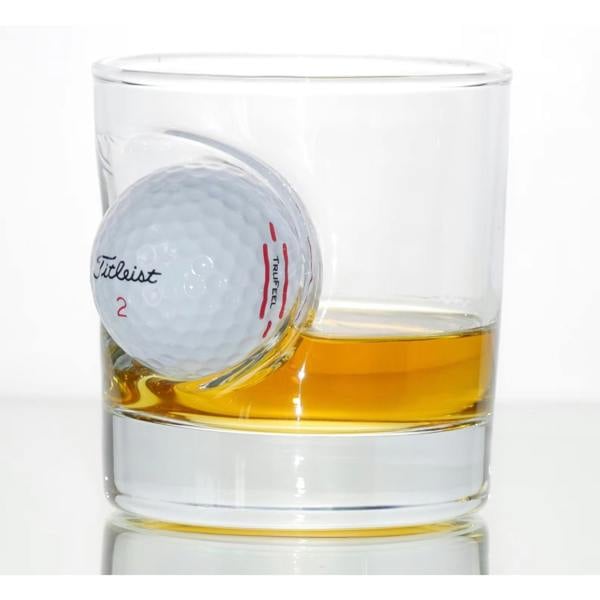 A personalised whisky tumbler by Abode Home & Gifts with a real Titleist golf ball embedded in the side, filled with amber spirit.