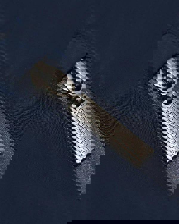 Lambretta Heaton Mens Shower-Resistant Mod Ska Hooded Lightweight Jacket Coat, close-up of the metal zipper with the brand name engraved, on navy blue fabric.