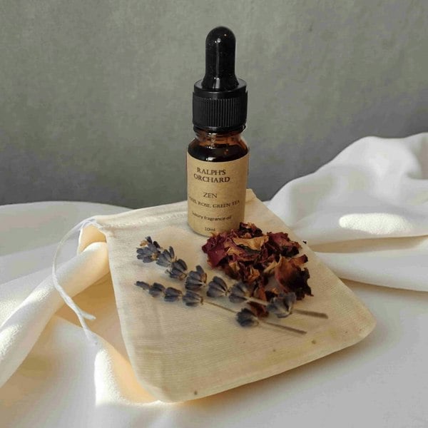 Bottle of 'Ralph's Orchard Zen' on a wooden board with dried flowers against a neutral background